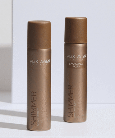Alix Avien Paris Shimmer Sparkling Ivory kūno blizgesio purškikliai, du auksinės spalvos buteliukai minimalistinėje fotosesijoje